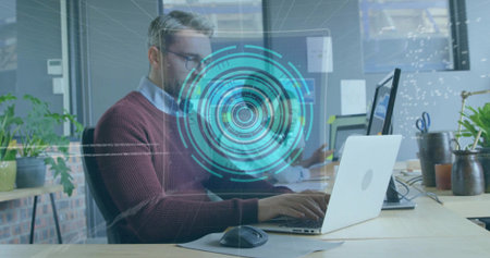 Typing mature man in maroon knit using laptop and mouse in open-plan office with holographic UI....
