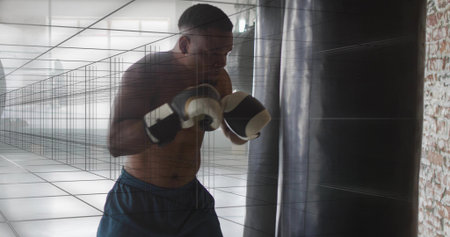 Training shirtless boxer hitting heavy punching bag at boxing gym, wearing gloves and navy shorts. Athlete, focus, intensity, fitness, discipline, studio, gridの写真素材