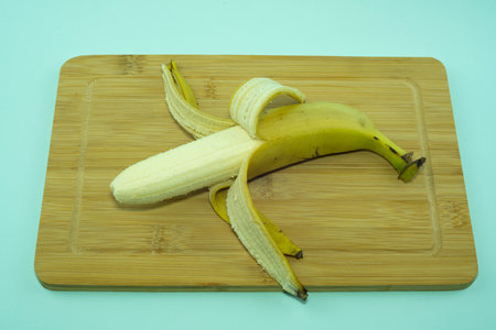 Banana, peeled in half on a cutting board. Isolated not blue background.の写真素材