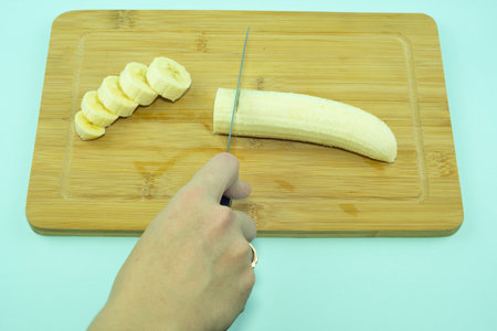 Peeled banana on a cutting board with chopped pieces. Banana on a cutting board with a kitchen knife...