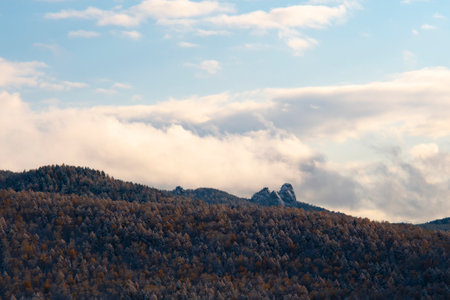 Highlands with rocks on a layer of snow. Mountains against a blue sky with white clouds.の写真素材