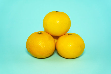 Yellow tangerines on a blue background. Tangerines arranged in the form of a pyramid.の写真素材
