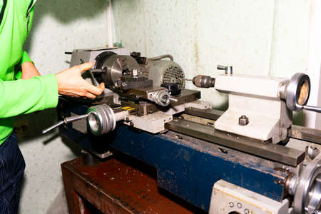 A man sets up a lathe for processing a part. Part groove on a lathe. Front side of the lathe....