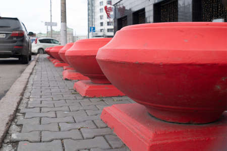 Red flower beds on the sidewalk near the roadway. The car is parked on the side of the road. Close-up.の写真素材