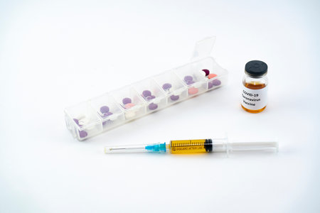 A syringe with a vaccine, a box for daily intake of pills and an ampoule with a coronavirus vaccine. Medical preparations on a white background. Protect yourself prematurely from disease.の写真素材