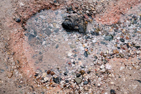 Natural spring of fresh water from a stone embankment. A source of water in the natural environment.