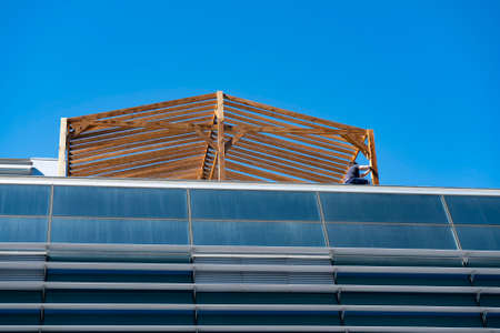 The timber frame of the extension on the roof of the building. A worker erecting an extension on the...