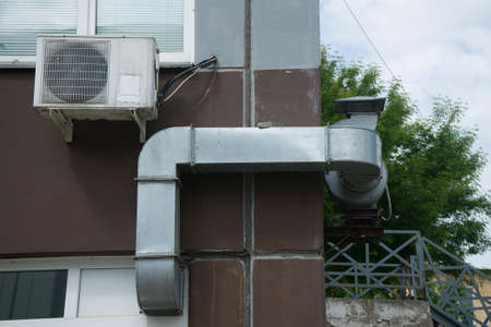 Ventilation pipe made of square profile with fan. Galvanized pipe on the facade of the building.の写真素材