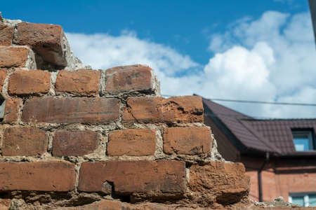 Old brown brick wall against the blue sky. Background texture. Old crumbling brick of a dilapidated time.の写真素材