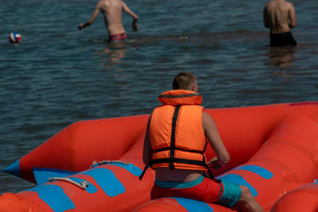 A man in a life jacket on a towed water tubing. The tubing attraction is towed by a jet ski. Active...