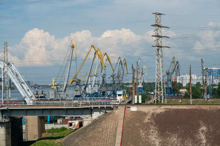 The loose abutment of the railway bridge against the background of harbor cranes.Railway bridge with...