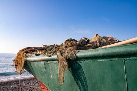 Fishing tackle on the stern of the ship. Fishermans green boat on the seashore. Boat against the...