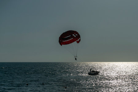 A man soars on a parachute over the sea behind a boat. Entertainment at the seaside resort.の写真素材