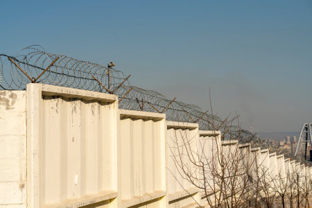 Concrete fence with barbed wire on top. Security fence of a military facility.の写真素材