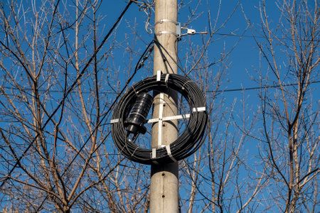 A thick coil of fiber optic cable on a concrete pole. Pillar with cable for communications.