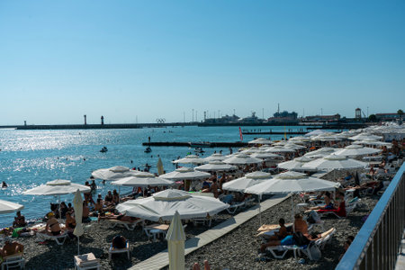 Sochi, Russia - July 05 2022: City beach on the seashore with sun loungers and umbrellas. Beach with vacationing tourists on the seashore on a sunny day.の写真素材