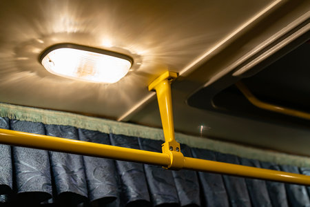 Lighting lamp on the ceiling of the bus above the handrail. Lighting in public transport.の写真素材