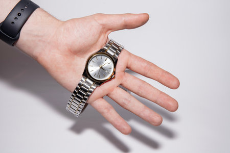 A watch with hands on a human palm. Electronic watch with a silver bracelet. Wristwatch.