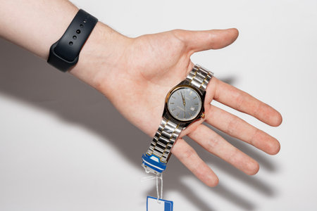 A watch with hands on a human palm. Electronic watch with a silver bracelet. Wristwatch.