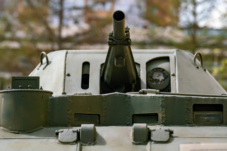 A green tank turret with a gun against the backdrop of a city. Military equipment in the city.