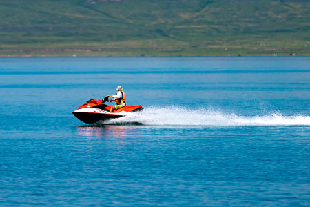 A man in a life jacket rides a jet ski on a lake. Active recreation on the lake.