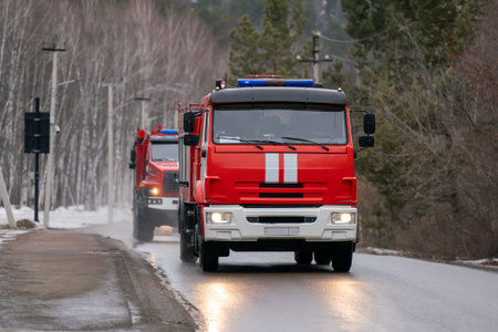 A red fire truck drives along a country road in winter. Firefighters rush to respond to a call.
