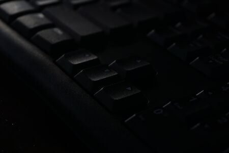 close up black computer keyboard on wooden table. Black and dark workplace