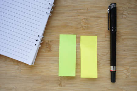 note book, pen and sticky paper memo on the wooden table backgroundの写真素材