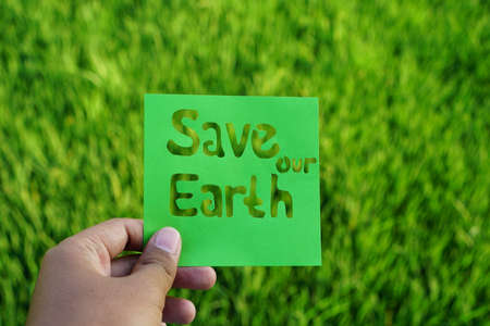 Hand holding word save our earth with green rice field and sky background. Earth day, environmental campaign Clean Natureの写真素材