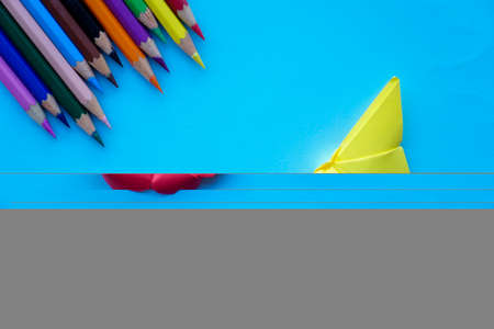 Arrange of pencils color and some origami paper with paper color background. Back to school concept