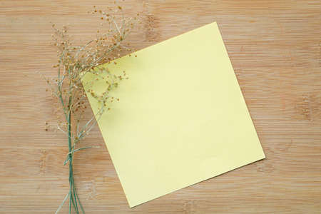 dry wild grass flower on wooden background and stationery blank paper. copy space for greeting...