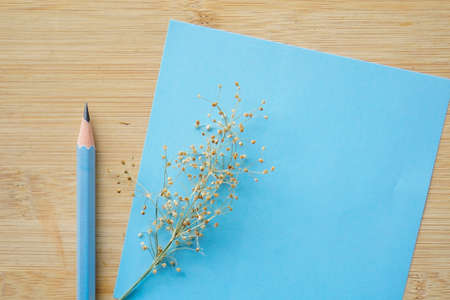 dry wild grass flower on wooden background and stationery blank paper. copy space for greeting quote, advertisingの写真素材