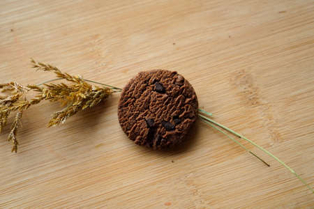 chocolate cookies and dark chocolate grain on wooden board background. for text concept advertisingの写真素材