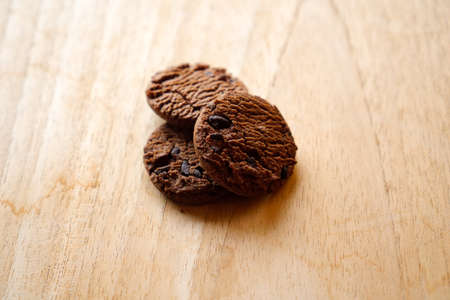 chocolate cookies and dark chocolate grain on wooden board background. for text concept advertising