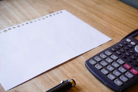 blank paper, ballpoint, and calculator for mockup concept on wooden board. finance, education backgroundの写真素材