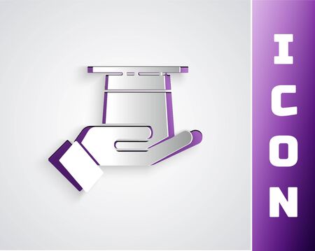 Paper cut Magician hat in hand icon isolated on grey background. Magic trick. Mystery entertainment concept. Paper art style. Vector Illustrationのイラスト素材