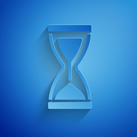 Paper cut Old hourglass with flowing sand icon isolated on blue background. Sand clock sign. Business and time management concept. Paper art style. Vectorのイラスト素材