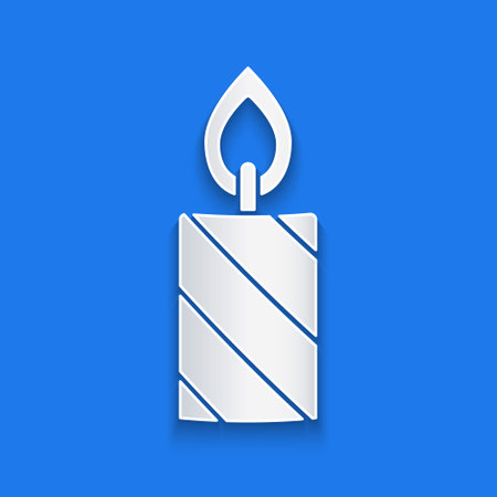 Paper cut Burning candle in candlestick icon isolated on blue background. Cylindrical candle stick with burning flame. Paper art style. Vectorのイラスト素材