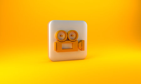 Gold Cinema camera icon isolated on yellow background. Video camera. Movie sign. Film projector. Silver square button. 3D render illustrationの写真素材