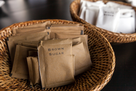 Many packs of brown sugar in bamboo tray prepared for coffee break during seminar event.の写真素材