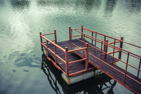 Old wooden and steel made jetty floating on the lakeside.の写真素材