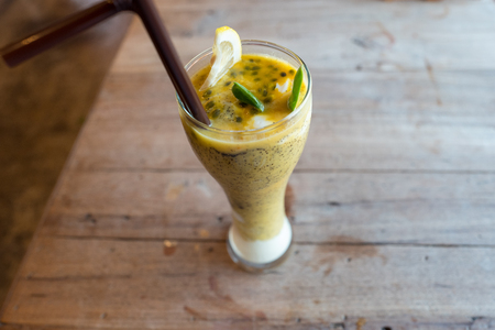 Healthy drinks, passion fruit mix with plain yogurt decorated with lemon and green leaf on wooden table.の写真素材