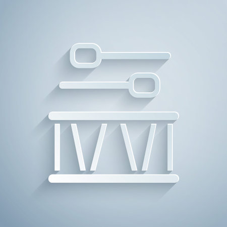 Paper cut Drum with drum sticks icon isolated on grey background. Music sign. Musical instrument symbol. Paper art style. Vectorのイラスト素材