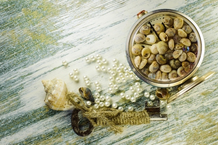 Scattered pearl beads and converted clock with seashells and old key on the old whiteboard.の写真素材