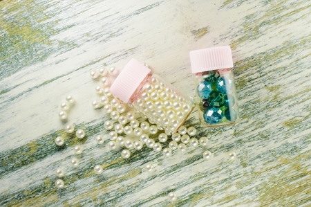 Scattered pearl beads and jars filled with pearls and blue beads on the old whiteboard.