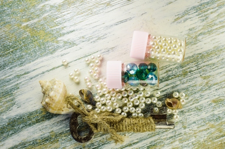 Scattered pearl beads and old key on the old whiteboard and jars filled with pearls and blue beads.の写真素材