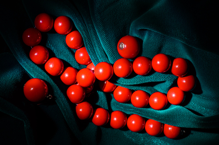 Red coral necklace and earrings at the dark green velvet background on the center of the frame.の写真素材