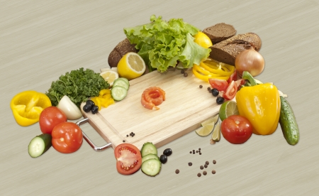 little piece of red fish surrounded by vegetables. tomatoes, cucumbers, onions, peppers, parsley, lemon, salad, bread, lemon, olivesの写真素材