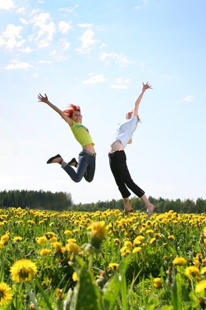 two happy girls jumping outdoorsの写真素材