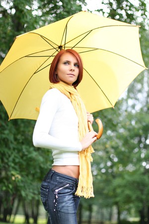 beautiful young girl under yellow umbrellaの写真素材